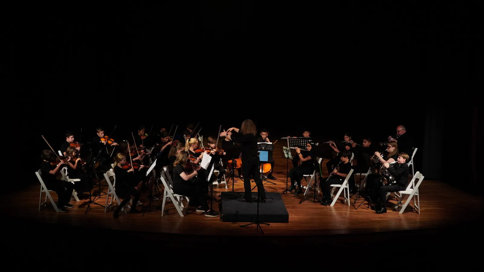 The North Carolina Youth Orchestra performing in the round on a darkened stage