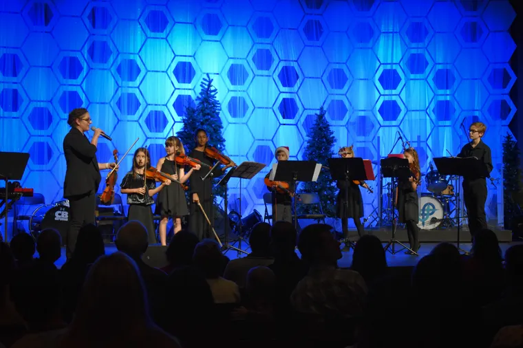NCYO strings students performing on a blue-lit stage