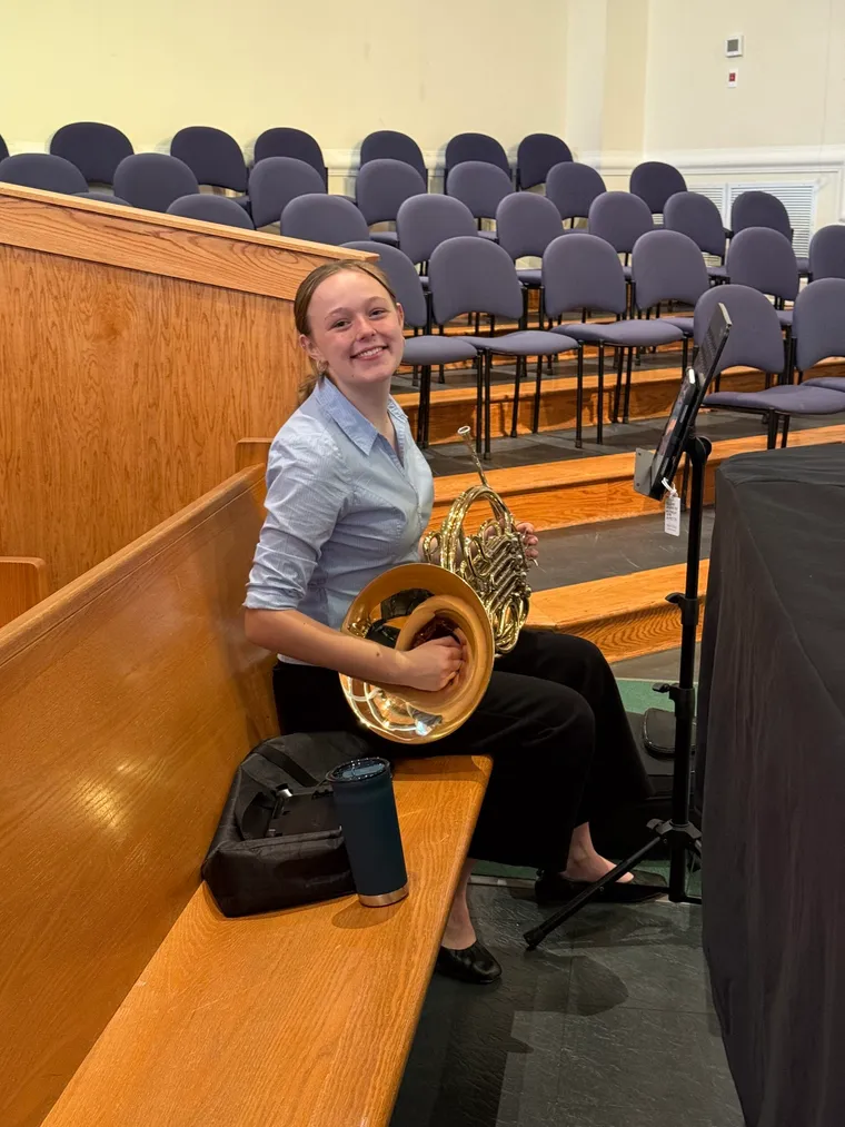 A young student with a French horn at Instrument Discovery Day