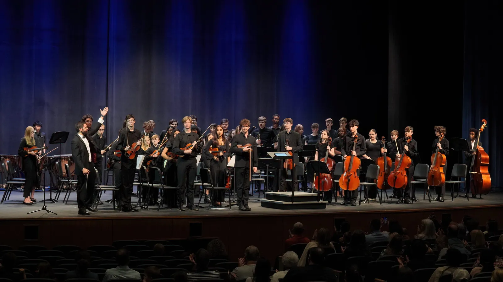 The full North Carolina Youth Orchestra performing on a darkened stage
